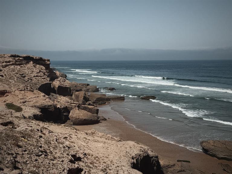 Küstenlandschaft mit felsigem Ufer und sanften Wellen am Meer