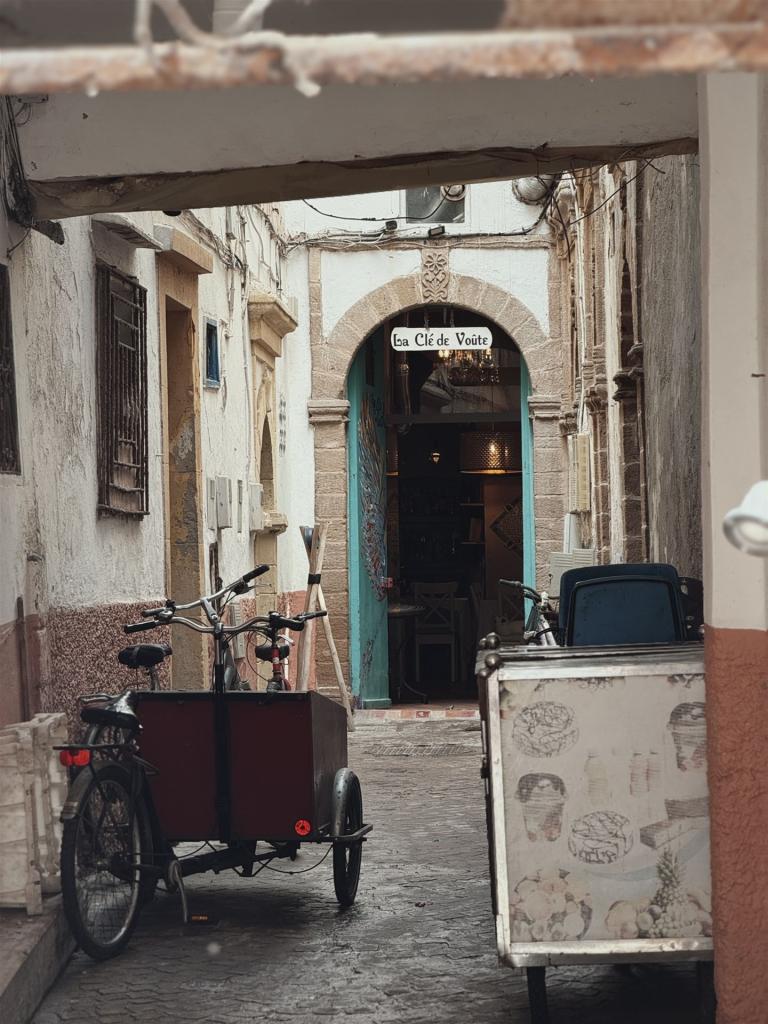 Eine schmale Gasse in europäischem Stil mit einem Fahrrad und zwei historischen Karren.