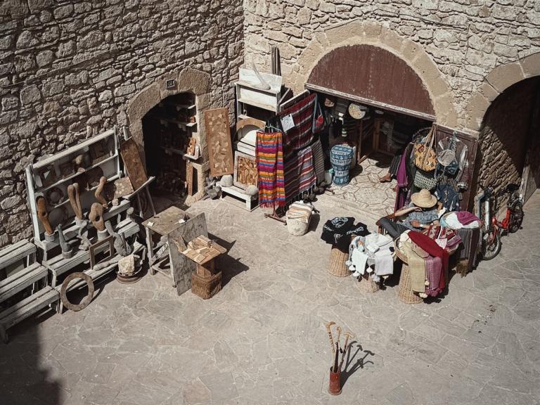 Marktstände mit Textilien und Waren in einer historischen Steinpassage