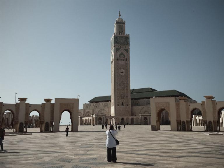 Ein großer Hof mit einem hohen Minarett und traditioneller islamischer Architektur.