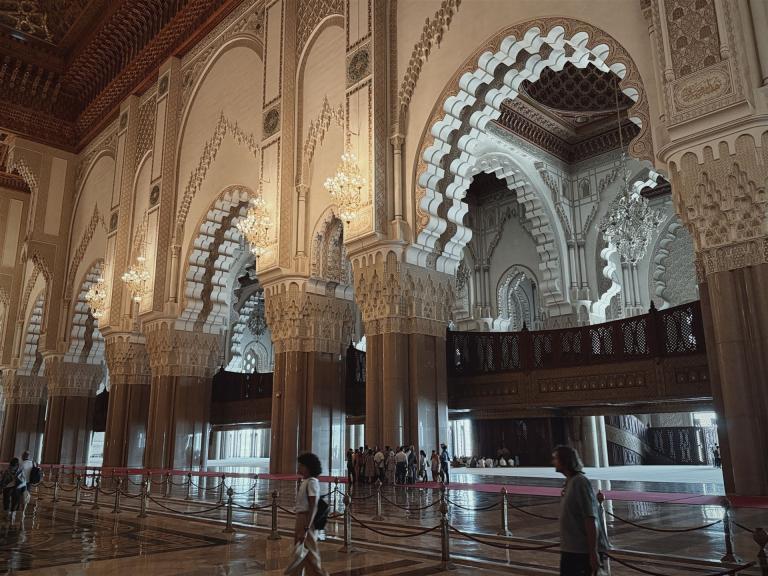 Monumentaler Innenraum einer Moschee mit kunstvollen Bögen, Säulen und Stuckverzierungen.