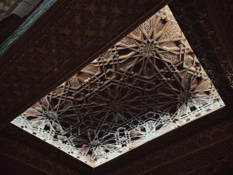 Eine detailreiche Darstellung eines komplexen geometrischen arabeskenartigen Musters an einer Decke.