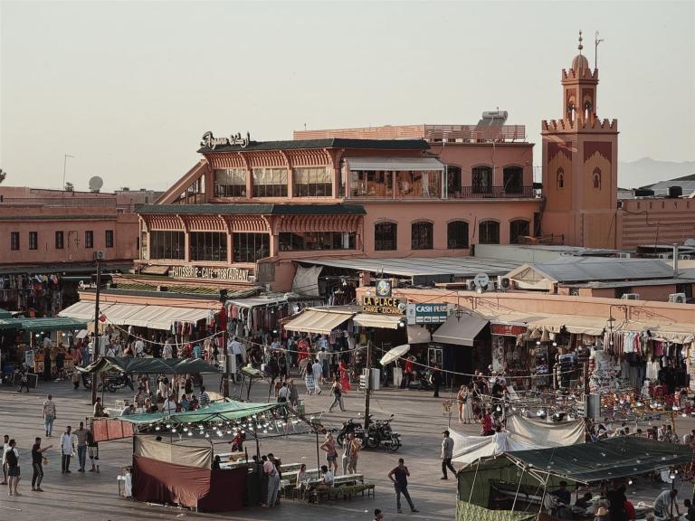 Ein geschäftiger Marktplatz in einer Altstadt mit vielen Ständen und historischen Gebäuden.